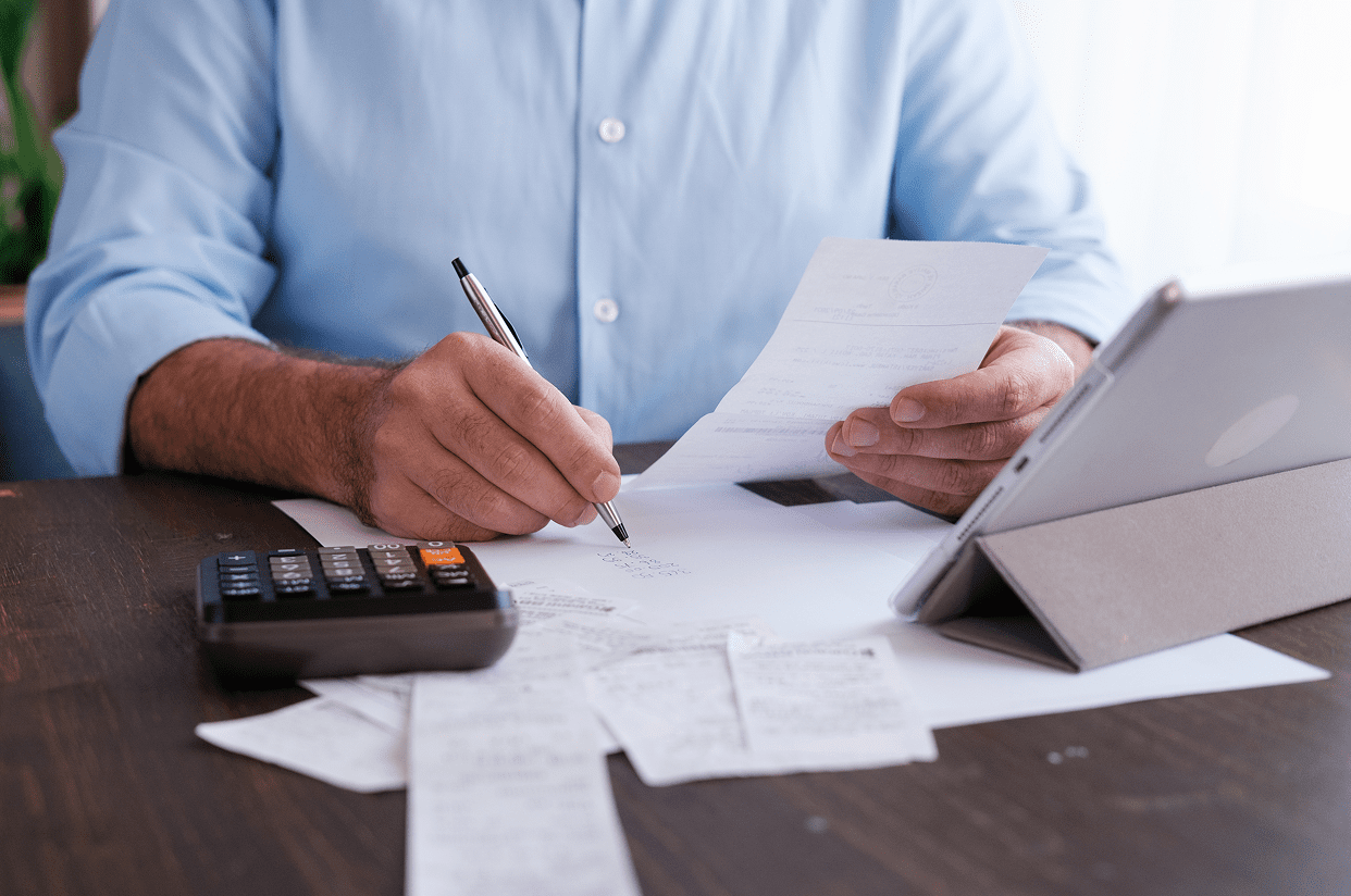 Man calculating expenses with tablet and receipts.